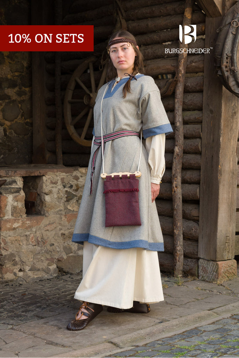 Person in historical costume standing in front of a wooden building with Burgschneider branding.